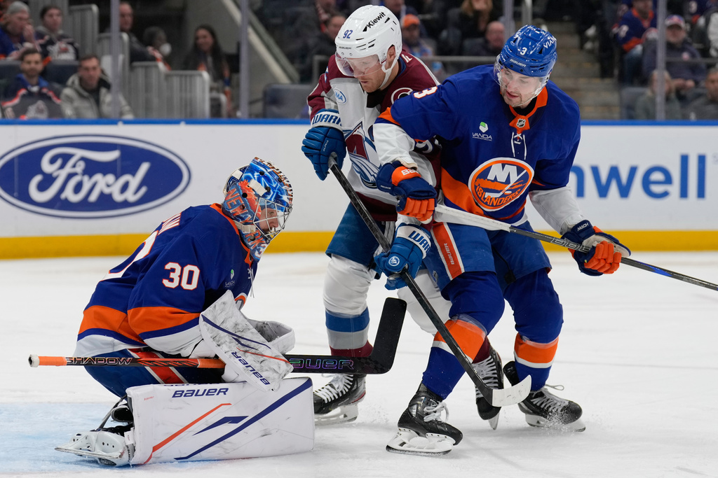 Colorado Avalanche's Gabriel Landeskog, center, and New York Islanders' Adam Pelech, right, watch as goaltender Ilya Sorokin makes a save during the third period of an NHL hockey game, Thursday, Dec. 4, 2025, in Elmont, N.Y. (AP Photo/Seth Wenig)