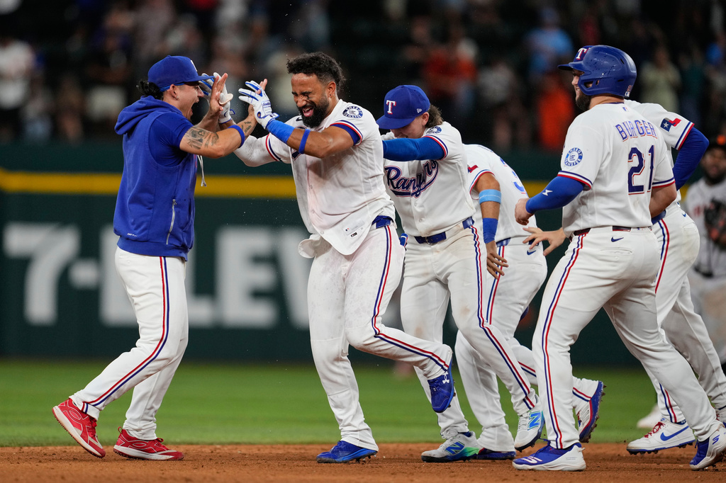 Texas Rangers' Alejandro Osuna, left, Ezequiel Duran, second from left, and the rest of the team celebrate Duran's run-scoring double in the ninth inning a baseball game against the San Francisco Giants in Arlington, Texas, Tuesday, Aug. 4, 2026. (AP Photo/Tony Gutierrez) CORRECTION: "run-scoring double" is correct not "run-scoring single"