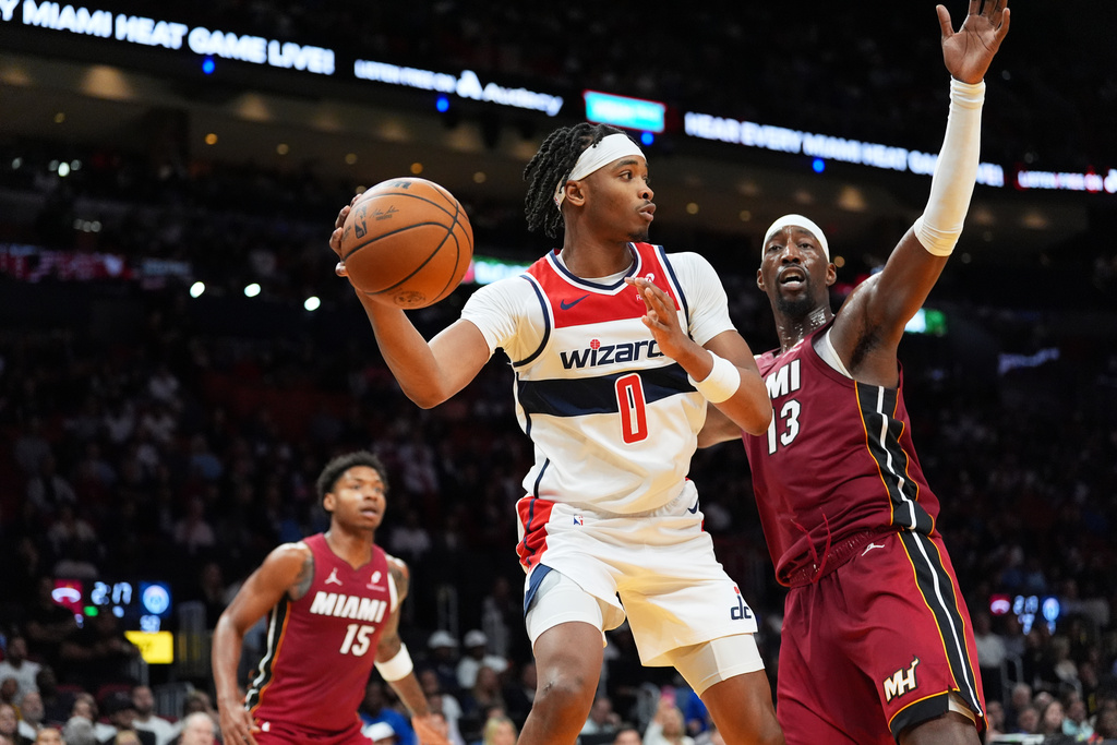 Washington Wizards guard Bilal Coulibaly (0) looks to pass around the defense of Miami Heat center Bam Adebayo (13) during the first half of an NBA basketball game, Tuesday, March 10, 2026, in Miami. (AP Photo/Rebecca Blackwell)