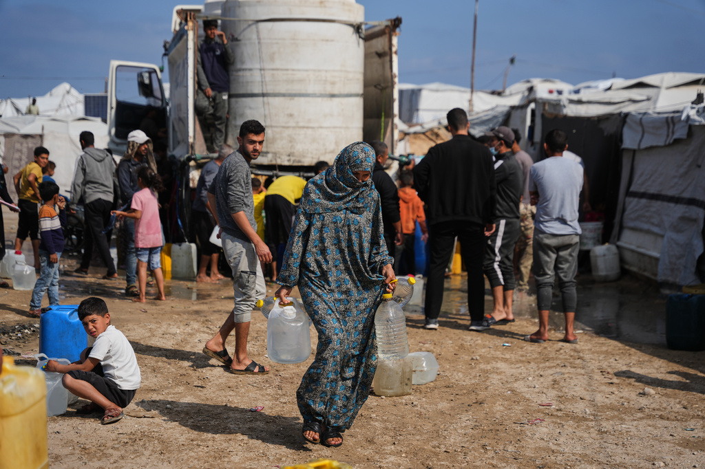 Samah Abu Daqqa, 33, carries jerrycans filled with water through a tent camp in Khan Younis, in the southern Gaza Strip, Thursday, April 30, 2026. (AP Photo/Abdel Kareem Hana)