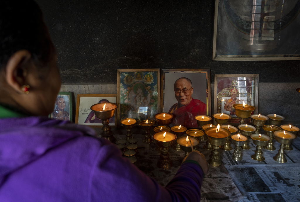 A Tibetan woman lights a butter lamp and offers a prayer in the remembrance of those who lost their lives in the recent earthquake, at a Tibetan camp in Lalitpur, Nepal, on Wednesday, Jan. 8, 2025. (AP Photo/Niranjan Shrestha)