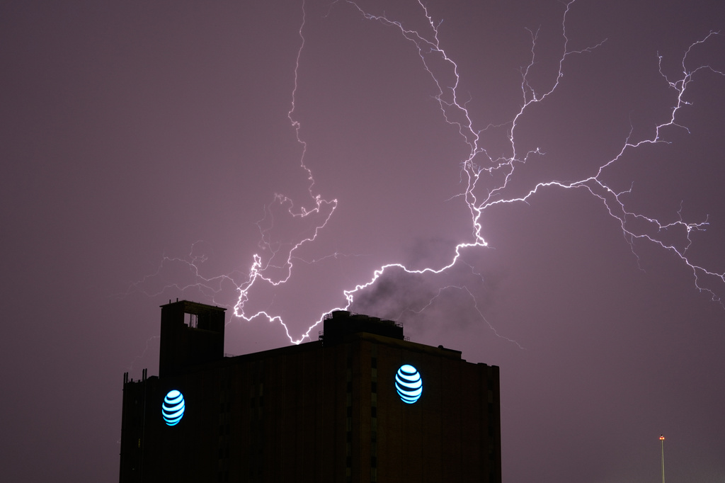 Lightning lights up the sky behind an AT&T building as a thunderstorm moves through the area Thursday, April 23, 2026, in Kansas City, Mo. (AP Photo/Charlie Riedel)