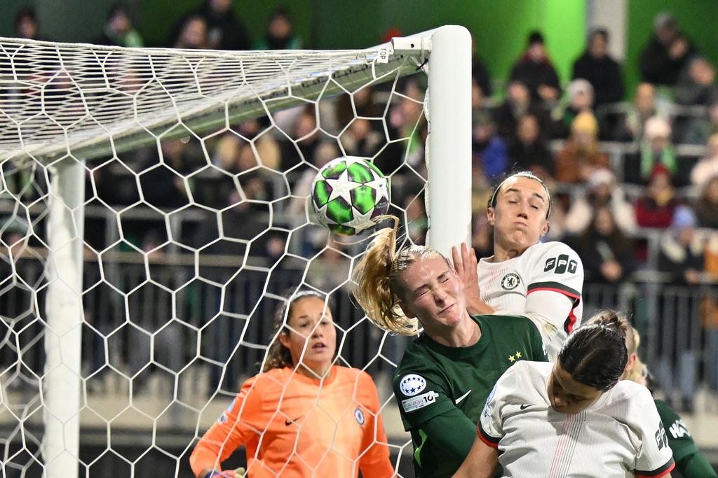 VfL Wolfsburg's Alexandra Popp, centre, heads the ball during the women's Champions League opening phase soccer match between VfL Wolfsburg and Chelsea in Wolfsburg, Germany, Wednesday, Dec. 17, 2025. (Swen Pförtner/dpa via AP)
