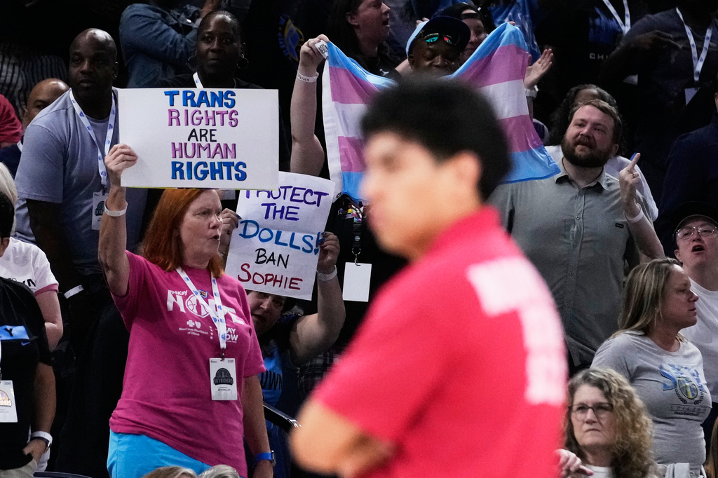 Fans stand up as they hold signs while Chicago Sky guard Natasha Cloud argues with former NBA center Enes Kanter Freedom during the second half of a WNBA basketball game against the Indiana Fever, Sunday, Aug. 23, 2026, in Chicago. (AP Photo/Nam Y. Huh)