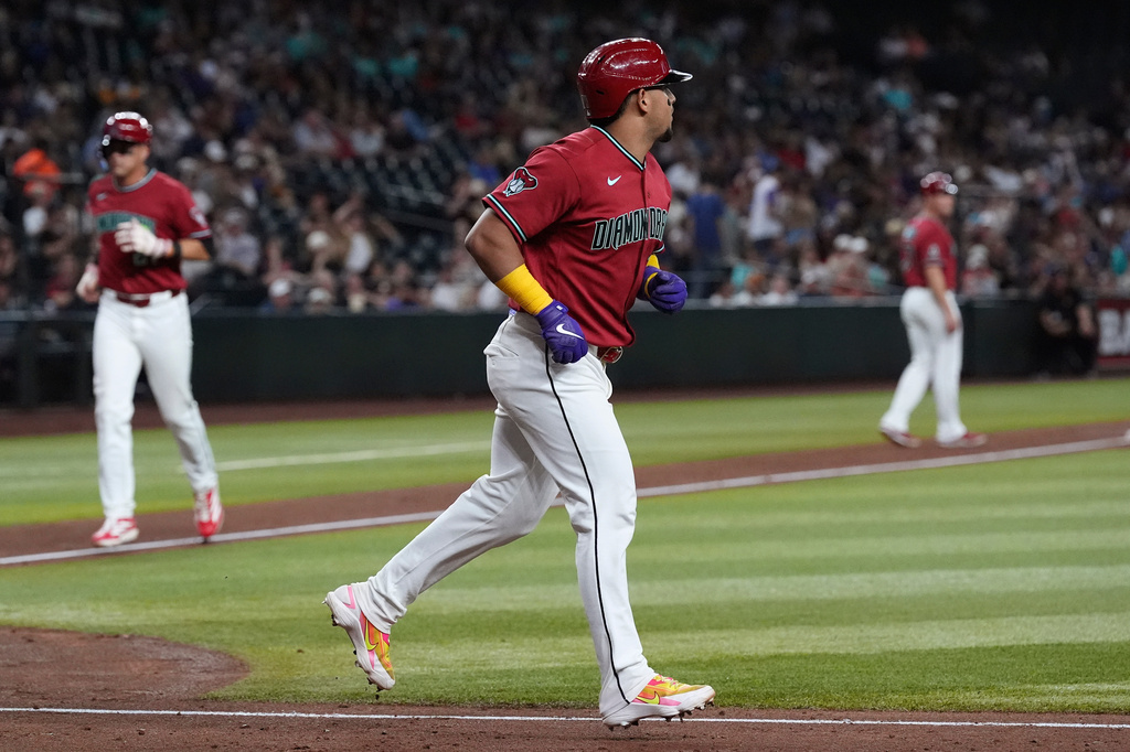 Arizona Diamondbacks' Gabriel Moreno, right, jogs to first base after earning a bases loaded walk as Diamondbacks' Lars Nootbaar, left, comes in to score a run against the San Diego Padres during the fourth inning of a baseball game, Wednesday, Aug. 5, 2026, in Phoenix. (AP Photo/Ross D. Franklin)
