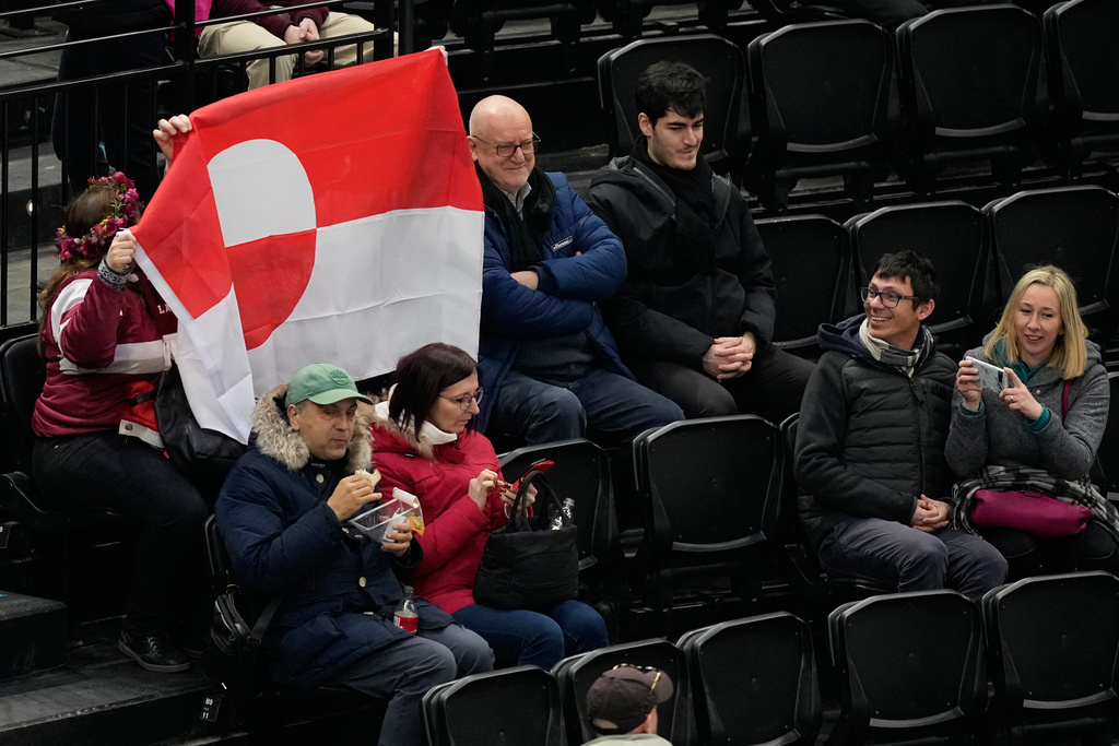 Fans hold Greenland national flag before a preliminary round match of men's ice hockey between United States and Denmark at the 2026 Winter Olympics, in Milan, Italy, Saturday, Feb. 14, 2026. (AP Photo/Hassan Ammar)