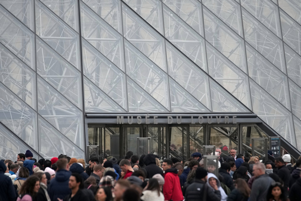People wait at the entrance of the Louvre museum as employees were set to vote on whether to extend a strike that shut the world's most visited museum, as unions protest chronic understaffing, building deterioration and recent management decisions Wednesday, Dec. 17, 2025 in Paris. (AP Photo/Christophe Ena)