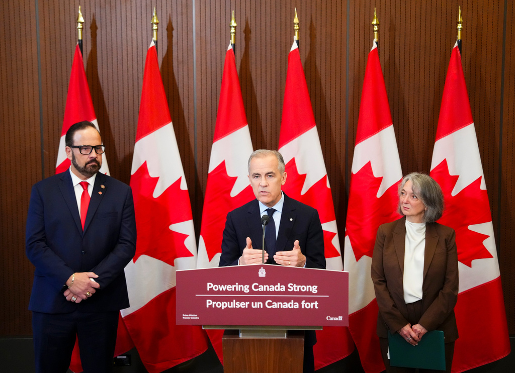 Prime Minister Mark Carney makes an announcement accompanied by Russ Shewchuk International Vice -President for International Brotherhood of Electrical Workers (IBEW) First District, left, and Minister of Environment and Climate Change Julie Dabrusin, right, on Parliament Hill in Ottawa on Thursday, May 14, 2026. (Sean Kilpatrick/The Canadian Press via AP)
