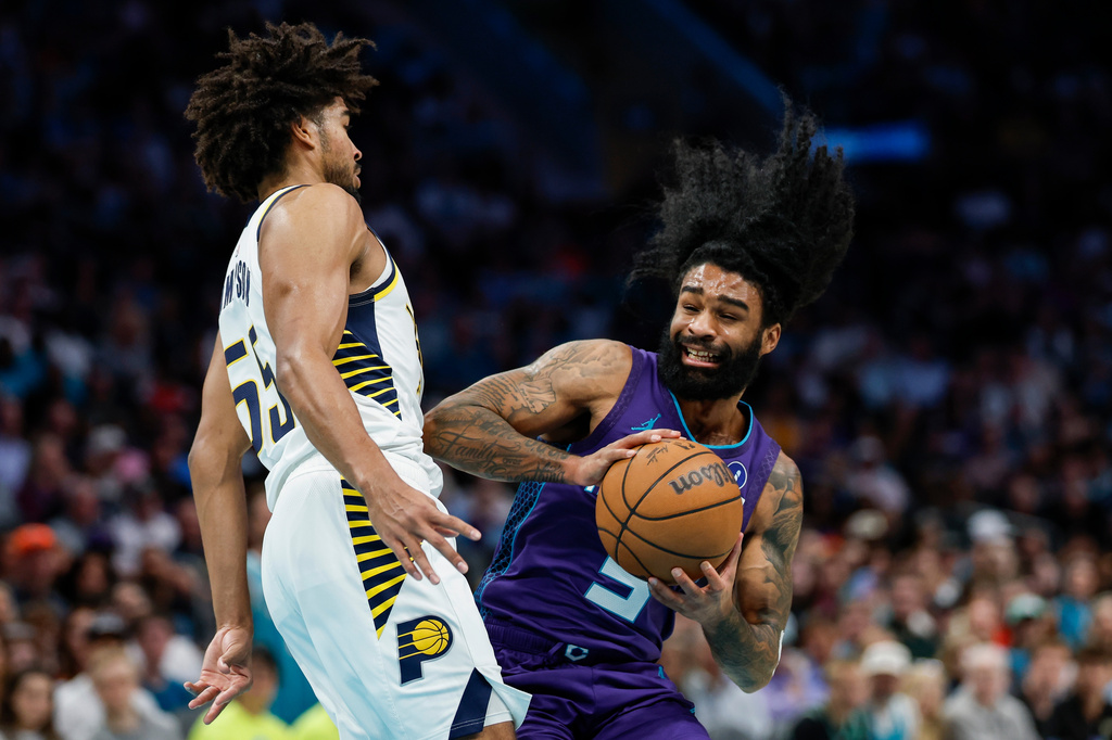 Charlotte Hornets guard Coby White, right, drives into Indiana Pacers guard Ethan Thompson, left, during the first half of an NBA basketball game in Charlotte, N.C., Friday, April 3, 2026. (AP Photo/Nell Redmond)