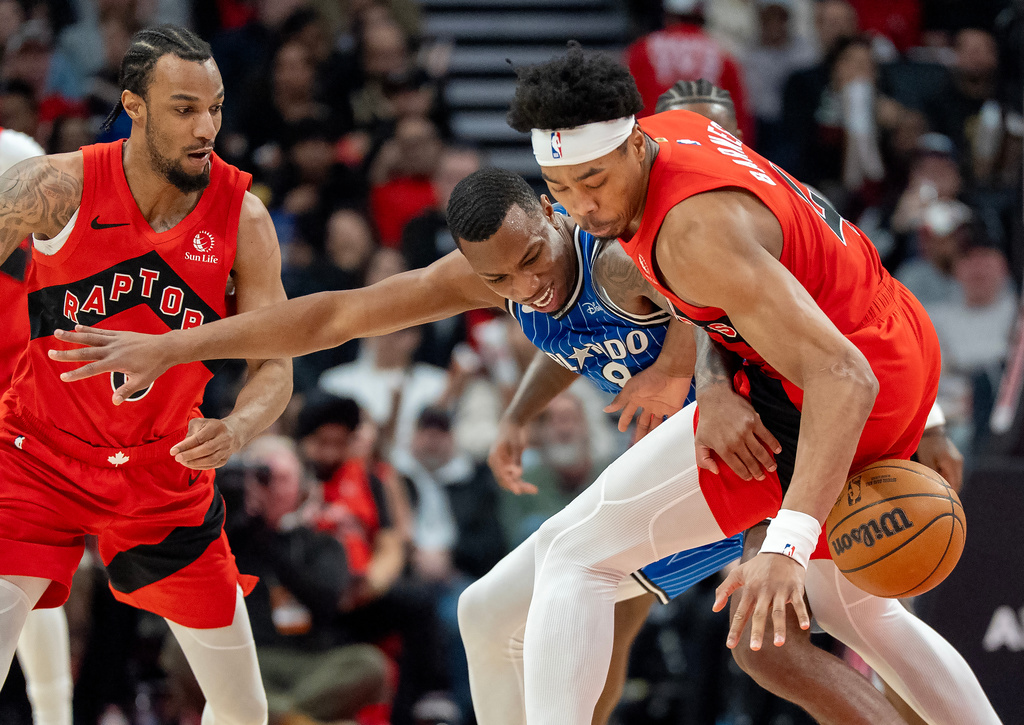 Toronto Raptors forward Scottie Barnes (right) strips the ball from Orlando Magic forward Jamal Cain (8) as Raptors guard A.J. Lawson (0) helps during first half NBA action in Toronto on Sunday, March 29, 2026. (Frank Gunn/The Canadian Press via AP)
