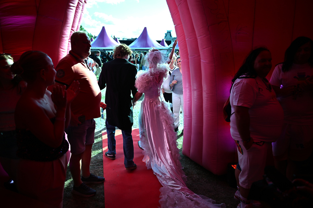 Newlyweds walk out of an inflatable chapel after tying the knot during a mass wedding ceremony in an inflatable chapel in Amsterdam, Netherlands, Thursday, Aug. 6, 2026, as part of Pride events celebrating 25 years since the Netherlands became the first country in the world to legalize same-sex marriage. (AP Photo/Mouneb Taim)