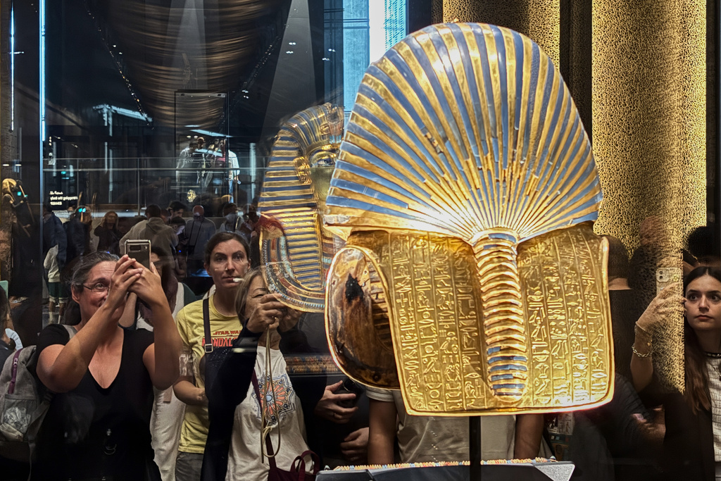 Visitors hold mobile devicecs in front of the golden burial mask of King Tutankhamun during the first day for visitors after the official opening of the Grand Egyptian Museum in Giza, Egypt, Tuesday, Nov. 4, 2025. (AP Photo/Amr Nabil)