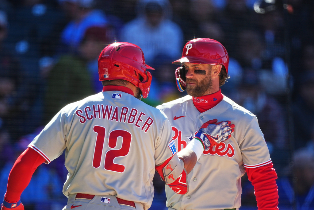 Philadelphia Phillies' Bryce Harper, right, congratulates Kyle Schwarber after his solo home run off Colorado Rockies relief pitcher Valente Bellozo in the fifth inning of a baseball game Friday, April 3, 2026, in Denver. (AP Photo/David Zalubowski)