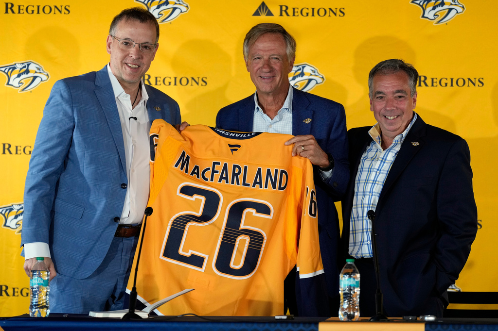 Nashville Predators new president of hockey operations and general manager Chris MacFarland, left, is presented a jersey by owner Bill Haslam, center, and CEO Sean Henry, right, during an introductory news conference at the NHL team's facility Wednesday, June 3, 2026, in Nashville, Tenn. (AP Photo/George Walker IV)