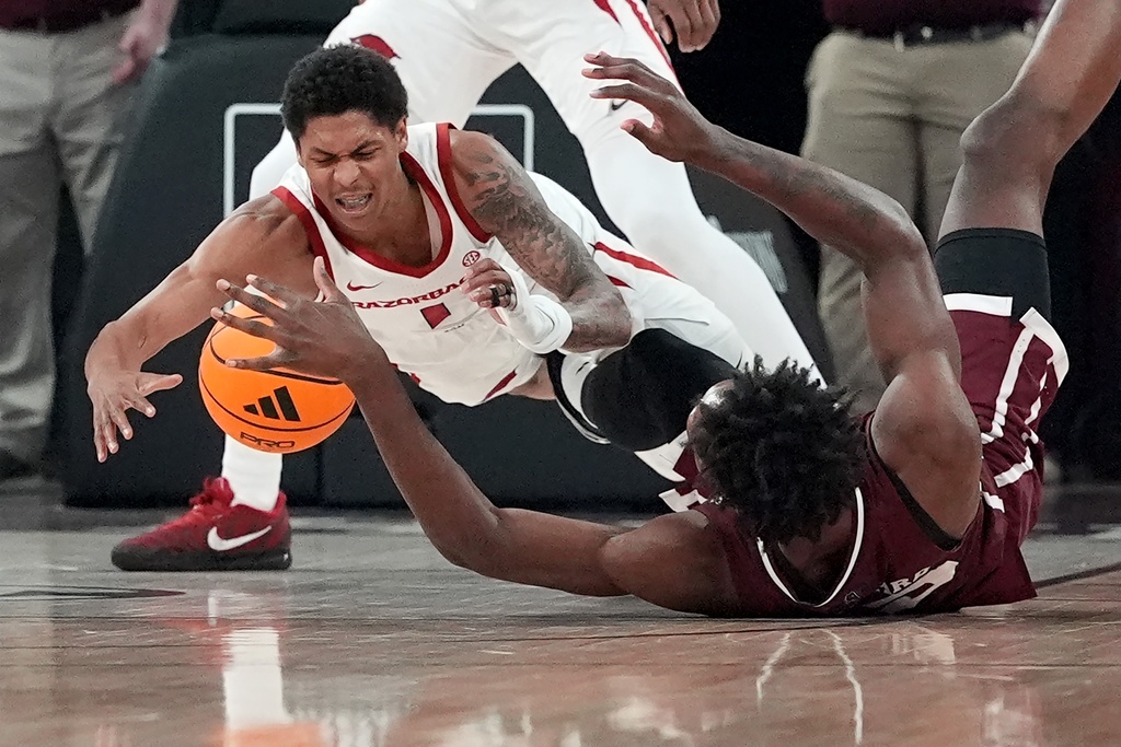 Arkansas guard Meleek Thomas (1) and Mississippi State's Quincy Ballard dive for a loose ball during the first half of an NCAA college basketball game, Saturday, Feb. 7, 2026, in Starkville, Miss. (AP Photo/Rogelio V. Solis)