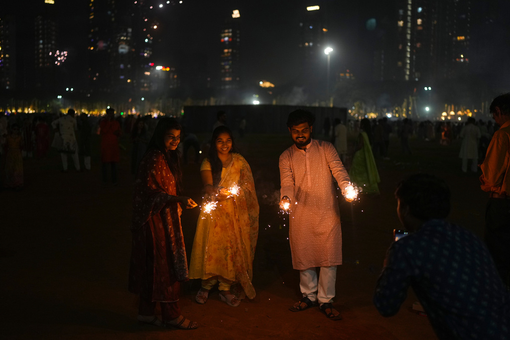 Friends light the fire crackers during the Diwali festival of lights in Mumbai, India, on Monday, Oct. 20, 2025. (AP Photo/Rafiq Maqbool)