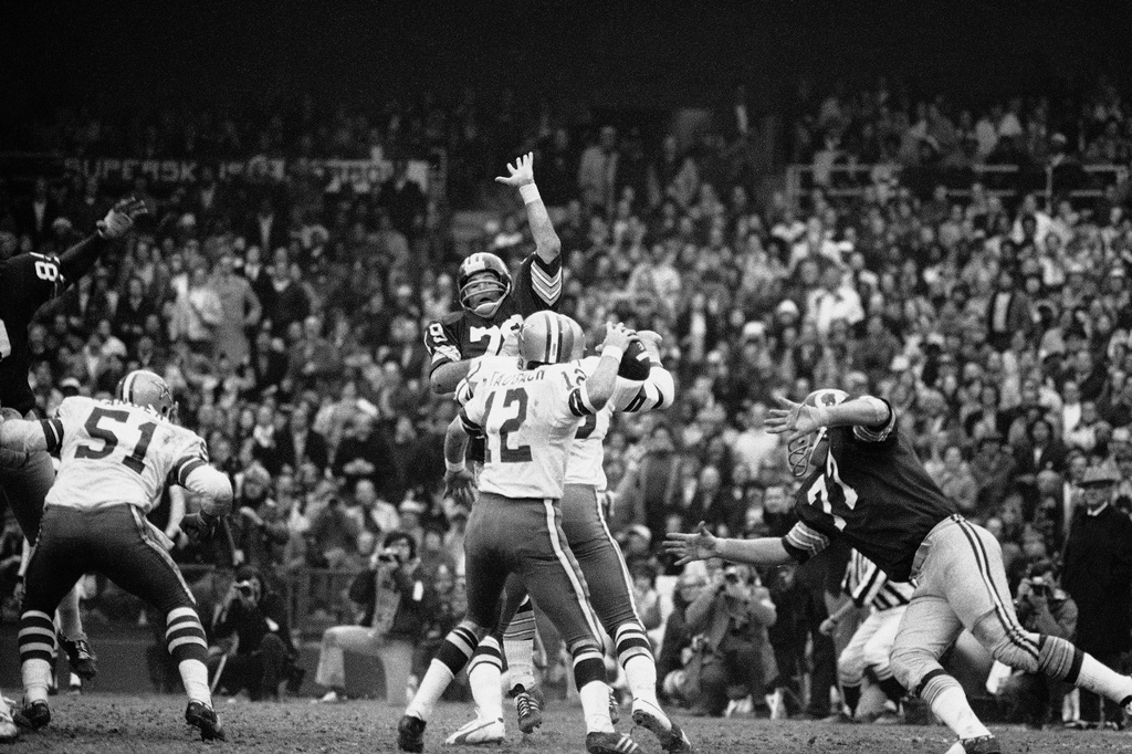 FILE - Dallas Cowboys quarterback Roger Staubach rears back to pass 22 yards to Ron Sellers (88) on a third down play late in the second quarter, Dec. 31, 1972. (AP Photo)