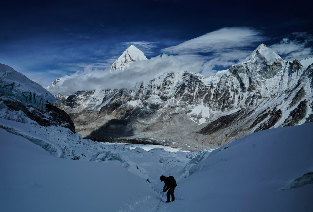 FILE - Mount Pumori, center left, looms in the background as a mountaineer negotiates Khumbu Icefall to descend to Everest Base Camp, in Nepal, May 4, 2025. (AP Photo/Pasang Rinzee Sherpa, File)