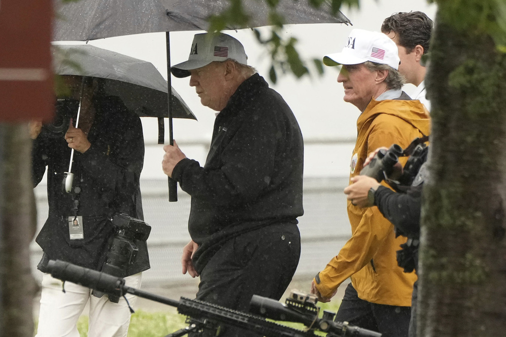 President Donald Trump walks carrying an umbrella alongside Interior Secretary Doug Burgum, right, at East Potomac Park golf course, Sunday, June 28, 2026, in Washington. (AP Photo/Mark Schiefelbein)