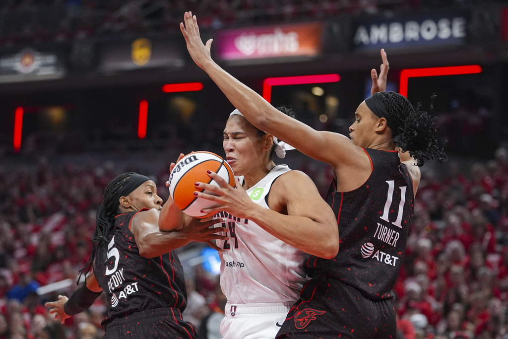Atlanta Dream forward Brionna Jones (24) cuts between Indiana Fever guard Shey Peddy (5) and forward Brianna Turner (11) in the first half of a WNBA basketball playoff game in Indianapolis, Tuesday, Sept. 16, 2025. (AP Photo/Michael Conroy)