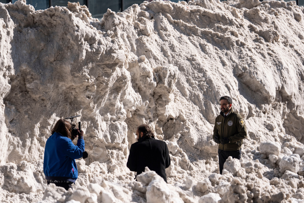 New York City Mayor Zohran Mamdani, right, stands backdropped by a pile of snow while recording a video during a visit to the Department of Sanitation's snow melting operations in New York, Thursday, Jan. 29, 2026. (AP Photo/Yuki Iwamura)