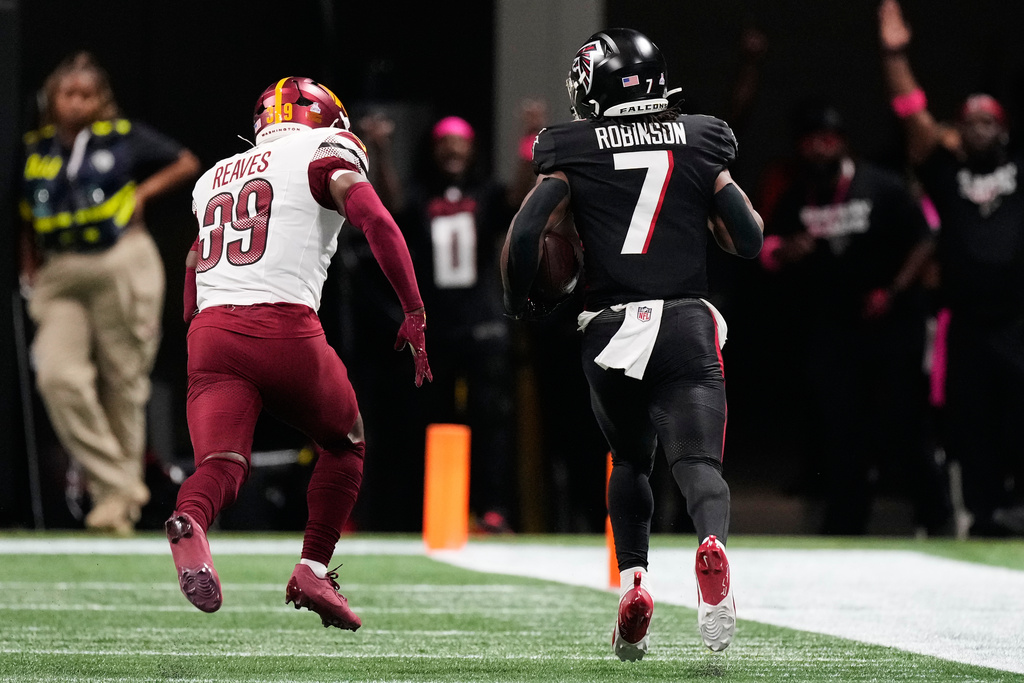 Atlanta Falcons running back Bijan Robinson (7) runs the ball past Washington Commanders safety Jeremy Reaves (39) during the second half of an NFL football game, Sunday, Sept. 28, 2025, in Atlanta. (AP Photo/Brynn Anderson)