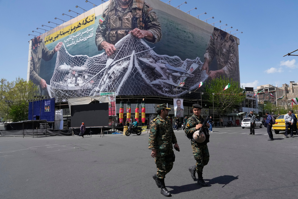 Two police officers walk in front of an anti-U.S. billboard depicting the American aircrafts into the Iranian armed forces fishing net with signs that read in Farsi: "The Strait of Hormuz will remain closed, The entire Persian Gulf is our hunting ground," at the Eqelab-e-Eslami, or Islamic Revolution square in downtown Tehran, Iran, Sunday, April 5, 2026. (AP Photo/Vahid Salemi)