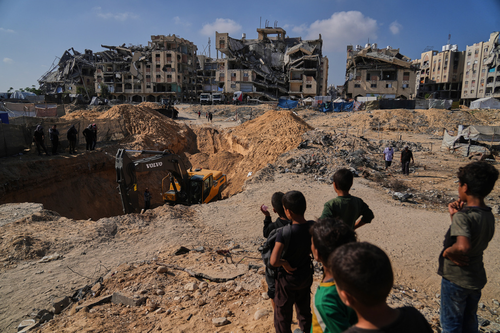 Palestinians watch as Egyptian machinery and workers search for the bodies of hostages in Hamad City, Khan Younis, in the southern Gaza Strip, Tuesday, Oct. 28, 2025. (AP Photo/Abdel Kareem Hana)