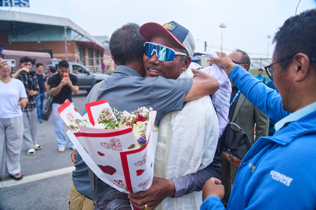 Renowned Sherpa mountain guide Kami Rita, center right, returning from Mount Everest after his record 32nd successful ascent is presented with shawls and flowers as he arrives at an airport in Kathmandu, Nepal, Friday, May 22, 2026. (AP Photo/Niranjan Shrestha)