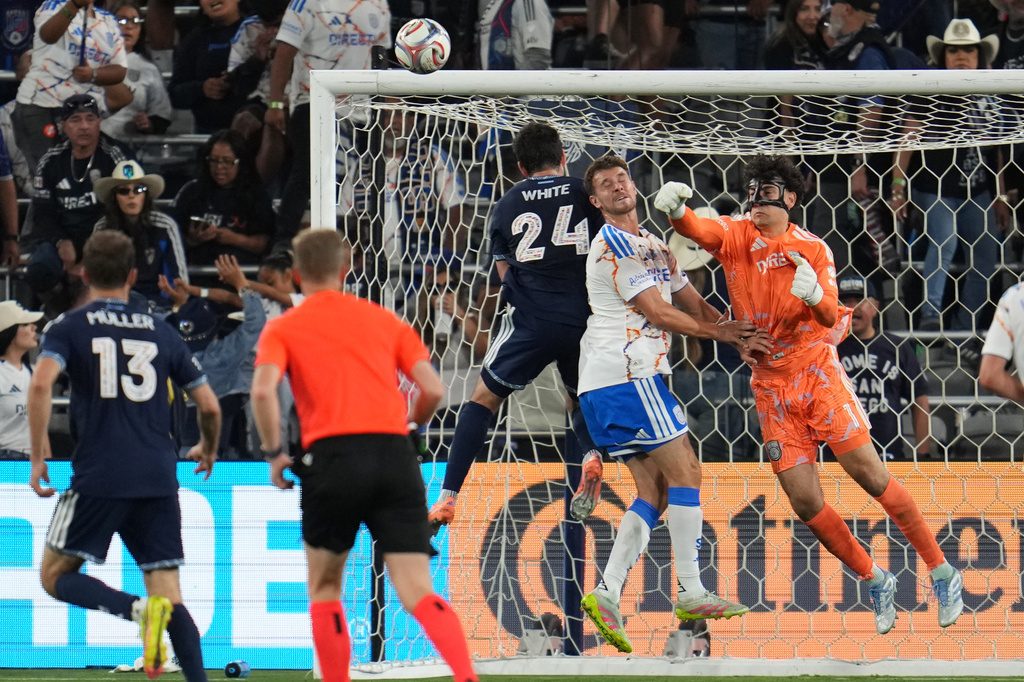 San Diego FC goalkeeper CJ Dos Santos, right, punches the ball clear over Vancouver Whitecaps FC forward Brian White (24) and San Diego FC defender Christopher McVey, center, during the second half of an MLS soccer match Saturday, May 23, 2026, in San Diego. (AP Photo/Gregory Bull)