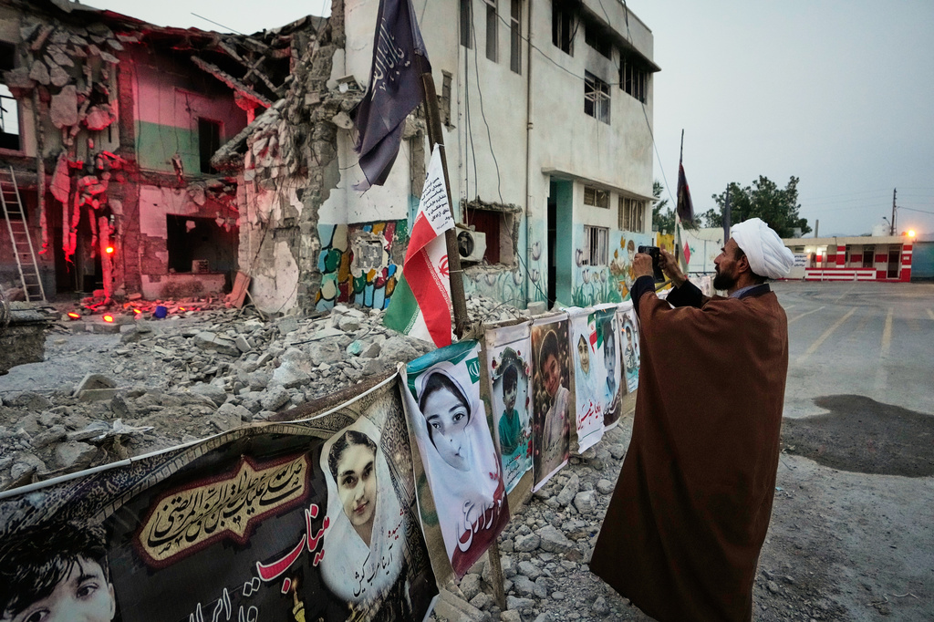 FILE - A cleric takes a photograph at the shattered Shajareh Tayyebeh school, which has become a place of mourning and a memorial to those killed in a U.S. airstrike on Feb. 28, in Minab, southern Iran, Monday, Sept. 7, 2026. (AP Photo/Vahid Salemi, File)