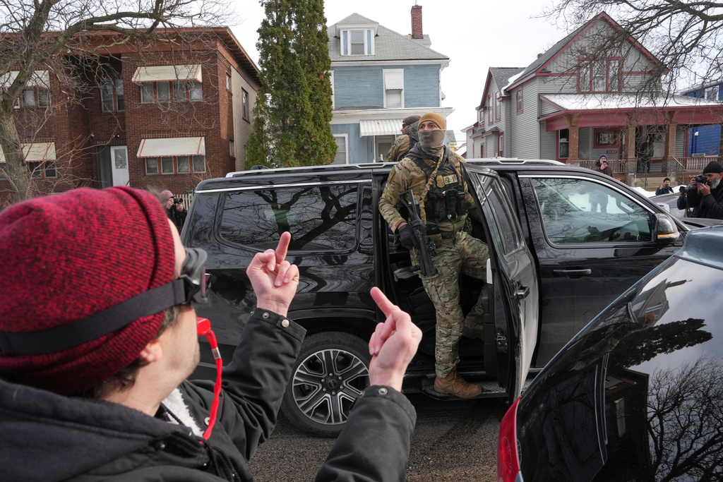 EDS NOTE: OBSCENITY - A person makes obscene gestures at Border Patrol agents after they've made arrests, Sunday, Jan. 11, 2026, in Minneapolis. (AP Photo/Adam Gray)