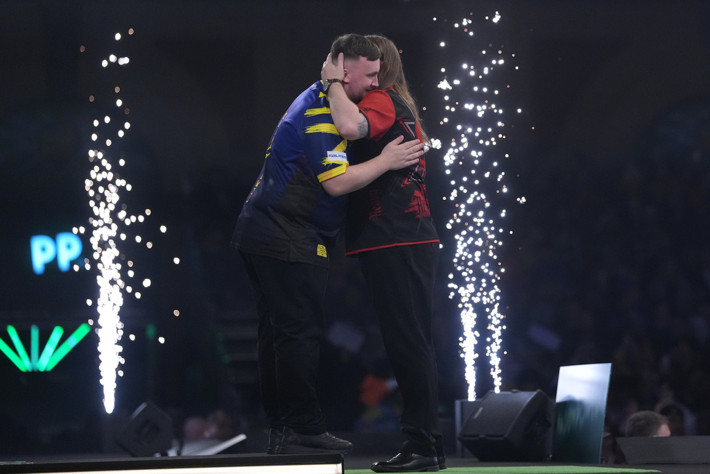 England's Luke Littler, left, reacts after winning the World Darts Championships semifinal match against England's Ryan Searle at Alexandra Palace in London, Friday, Jan. 2, 2026.(AP Photo/Dave Shopland)