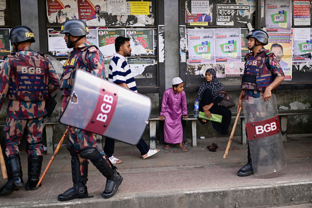 Security personnel walk past a bus stop as ousted Prime Minister Sheikh Hasina and her former ruling Awami League party called for a nationwide "lockdown" in protest against her trial, in Dhaka, Bangladesh, Thursday, Nov. 13, 2025. (AP Photo/Mahmud Hossain Opu)