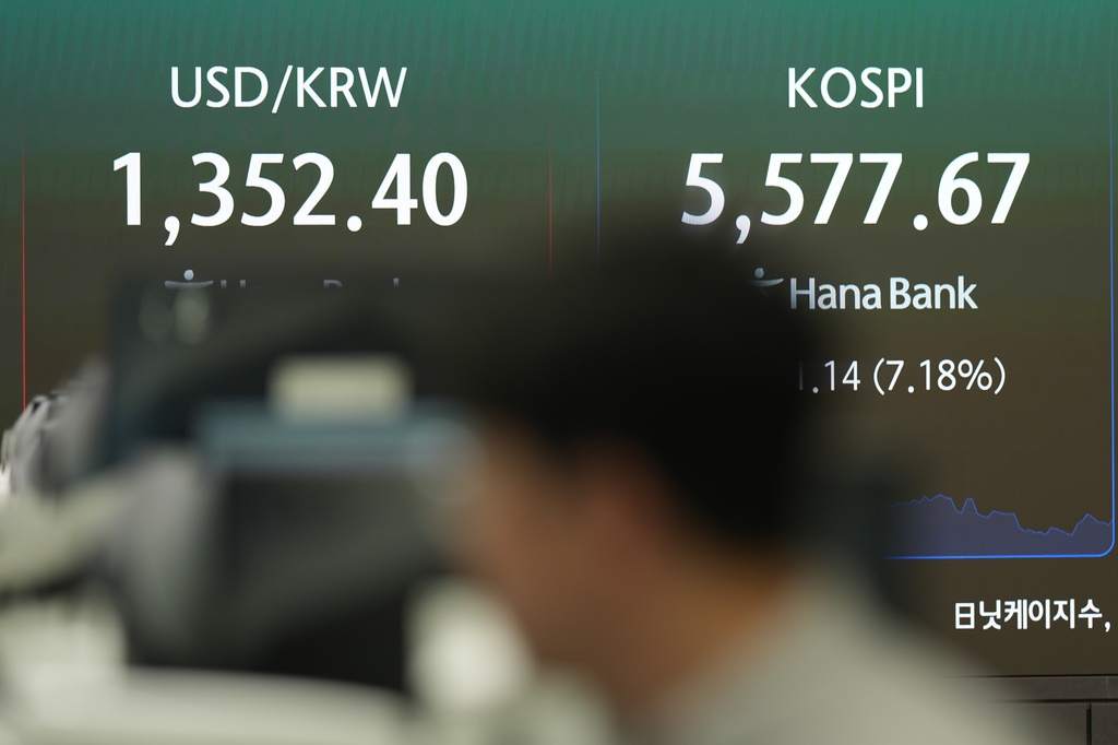 A dealer walks near the screens showing the Korea Composite Stock Price Index (KOSPI) and the foreign exchange rate between U.S. dollar and South Korean won at a dealing room of Hana Bank in Seoul, South Korea, Thursday, Oct. 15, 2026. (AP Photo/Lee Jin-man)