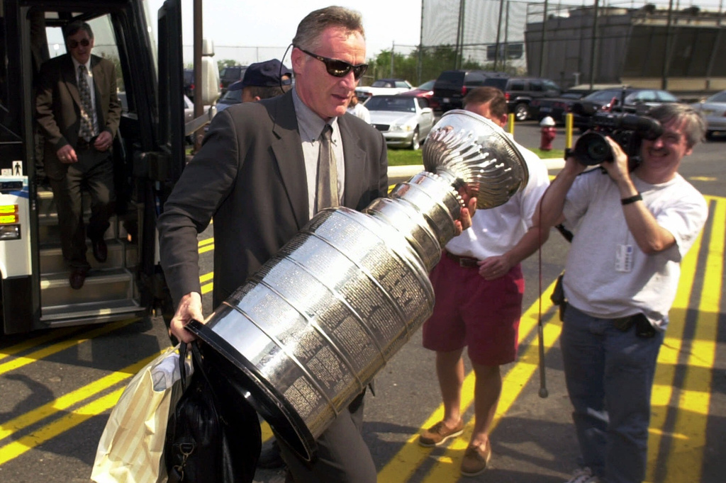 FILE - New Jersey Devils head coach Larry Robinson carries the Stanley Cup from the bus as the team arrives back in East Rutherford, N.J., June 11, 2000. (AP Photo/Daniel Hulshizer)