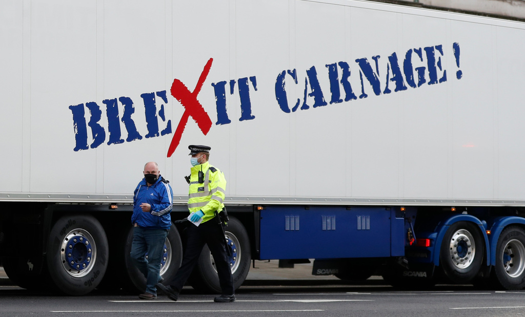 FILE - A policeman escorts the driver of a shellfish export truck as he is stopped for an unnecessary journey in London, Monday, Jan, 18, 2021. (AP Photo/Alastair Grant, File)