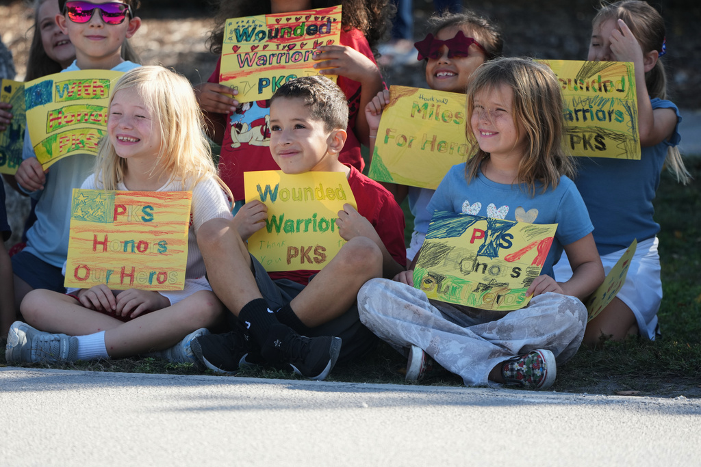Students from an elementary school hold signs in support as wounded veterans ride past in the annual Florida Keys Soldier Ride organized by the Wounded Warrior Project, Friday, Jan. 9, 2026, in Islamorada, Fla. (AP Photo/Lynne Sladky)