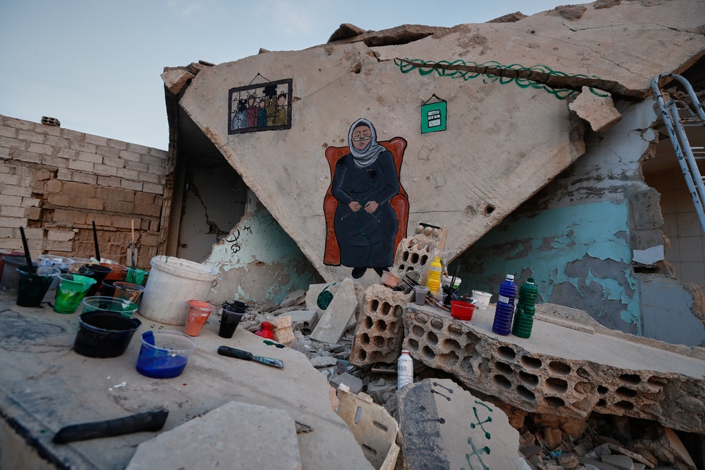 Paint and brushes sit on rubble next to a graffiti mural recently painted by a group of Syrian graffiti artists on the collapsed ceiling of a war-damaged house in Daraya, on the outskirts of Damascus, Syria, Monday, Nov. 3, 2025. (AP Photo/Omar Sanadiki)