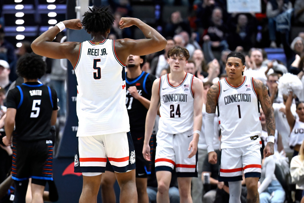 UConn forward Tarris Reed Jr. (5) flexes toward UConn guards Braylon Mullins (24) and Solo Ball (1) in the first half of an NCAA college basketball game against DePaul Blue, Saturday, Jan. 10, 2026, in Hartford, Conn. (AP Photo/Jessica Hill)