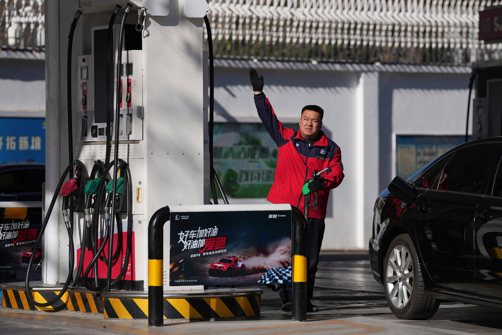 A gas station attendant gestures before pumping petrol into a car in Beijing, Wednesday, March 11, 2026. (AP Photo/Ng Han Guan)