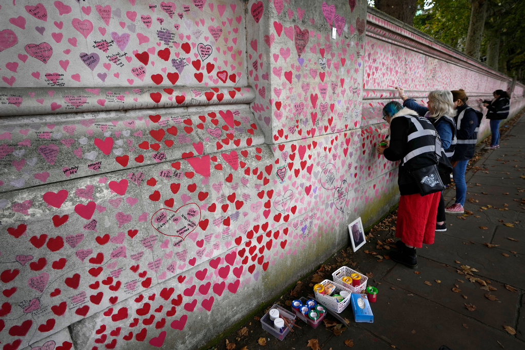 FILE - Volunteers work on the COVID-19 memorial wall in Westminster in London, Friday, Oct. 15, 2021. (AP Photo/Kirsty Wigglesworth, File)