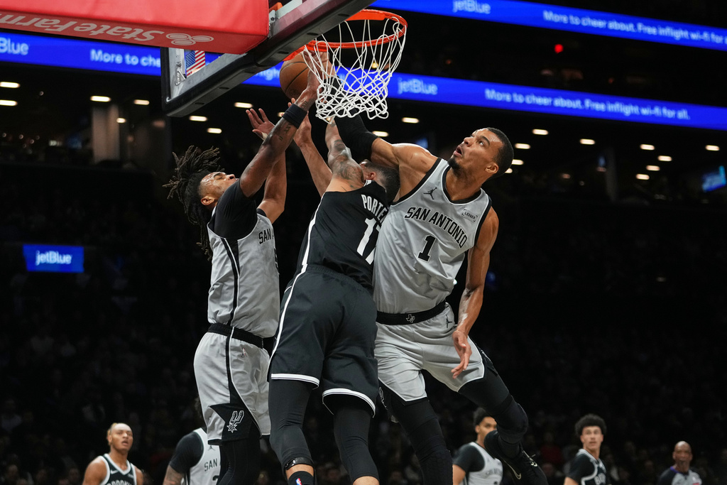San Antonio Spurs' Victor Wembanyama, right, and Stephon Castle, left, defend a shot by Brooklyn Nets' Michael Porter Jr. during the first half of an NBA basketball game Thursday, Feb. 26, 2026, in New York. (AP Photo/Frank Franklin II)