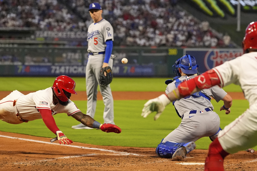 Los Angeles Angels' Luis Rengifo, left, scores on a double by Bryce Teodosio as Los Angeles Dodgers catcher Dalton Rushing, second from right, waits for the ball and first baseman Freddie Freeman, second from left, watches along with Zach Neto, right, during the fourth inning of a baseball game Tuesday, Aug. 12, 2025, in Anaheim, Calif. (AP Photo/Mark J. Terrill)
