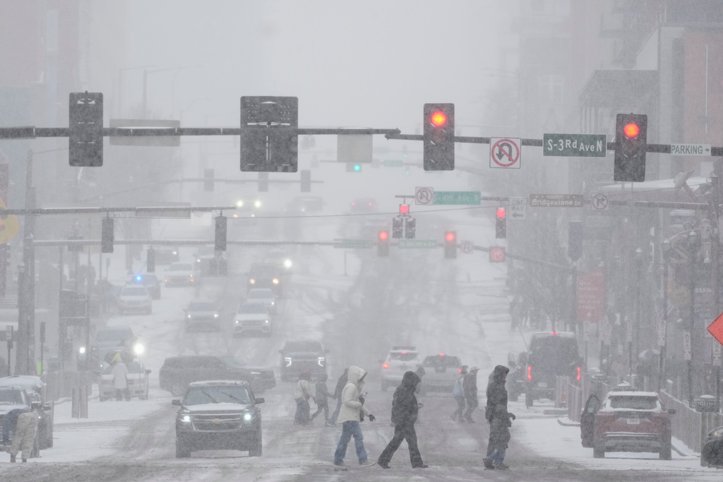 Pedestrians cross the street along Broadway during a winter storm Saturday, Jan. 24, 2026, in Nashville, Tenn. (AP Photo/George Walker IV)