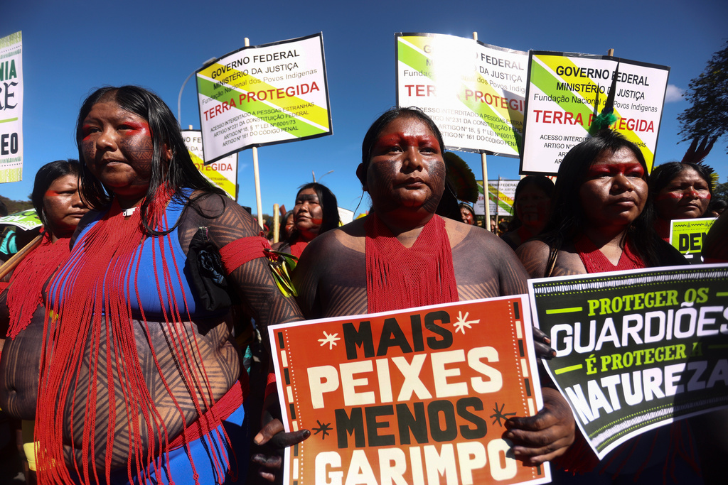 FILE - An Indigenous woman marches with a sign that reads in Portuguese "More fish, less mining," during the 20th annual Free Land Indigenous Camp in Brasilia, Brazil, April 23, 2024. (AP Photo/Luis Nova, File)