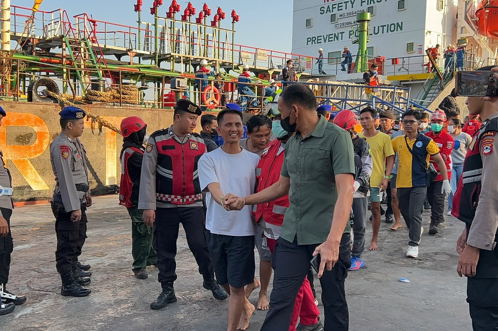 In this photo released by the Indonesia's National Search and Rescue Agency (BASARNAS), survivors from a passenger ferry overturned in bad weather in the Java Sea on Sunday are greeted by officials after disembarking a rescue ship in Banjarmasin, South Kalimantan, Monday, Sept. 14, 2026. (BASARNAS via AP)