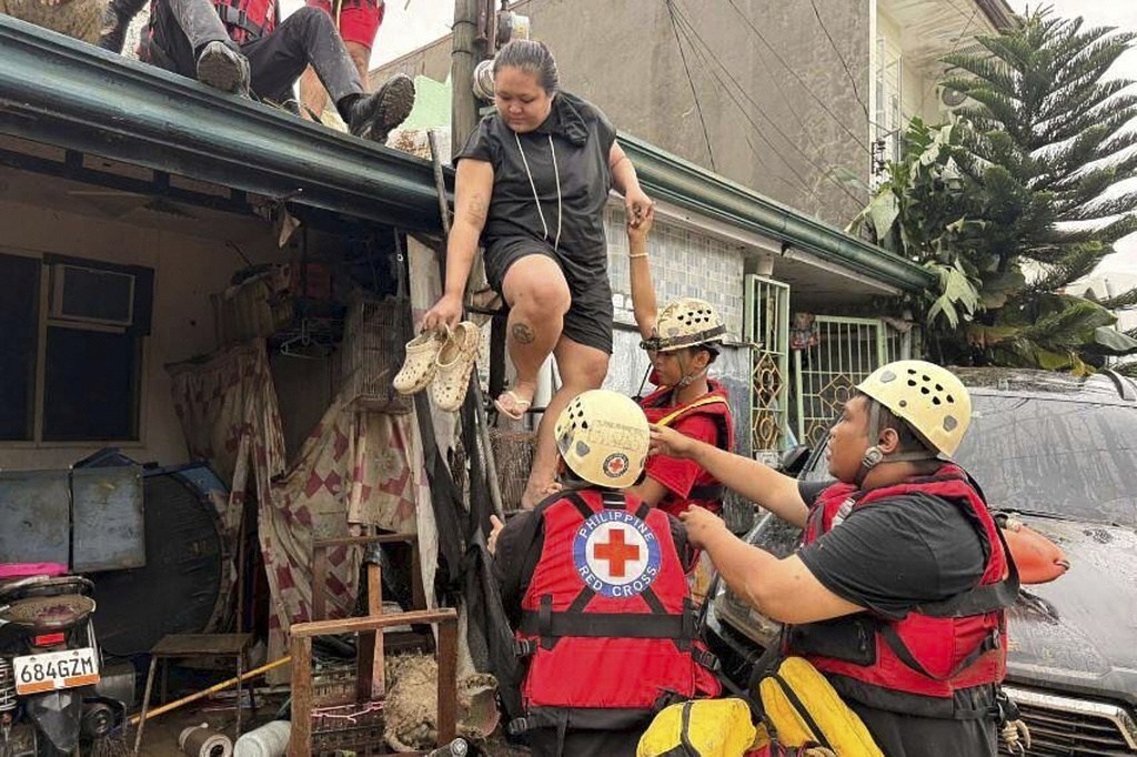 In this photo provided by the Philippine Red Cross, the Water Search and Rescue Team assists individuals trapped on a roof in the Talamban barangay of Cebu, Philippines, Tuesday, Nov. 4, 2025. (Philippine Red Cross via AP)