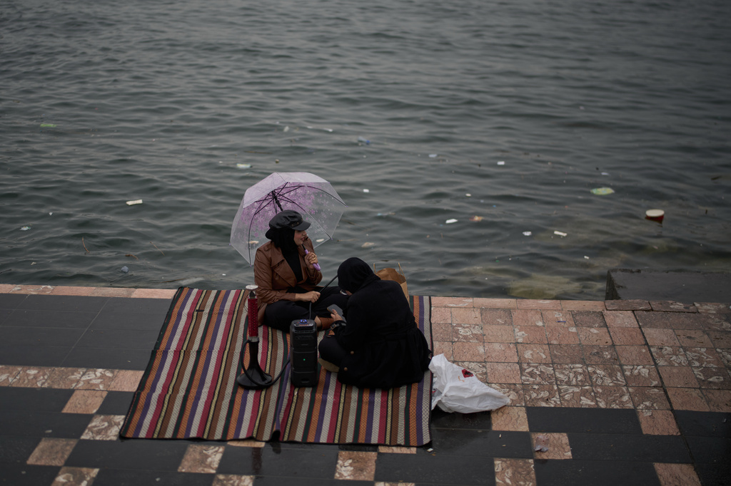 Women sit alongside the Shatt al-Arab River, on the corniche of Basra, Iraq, Thursday, March 26, 2026. (AP Photo/Leo Correa)