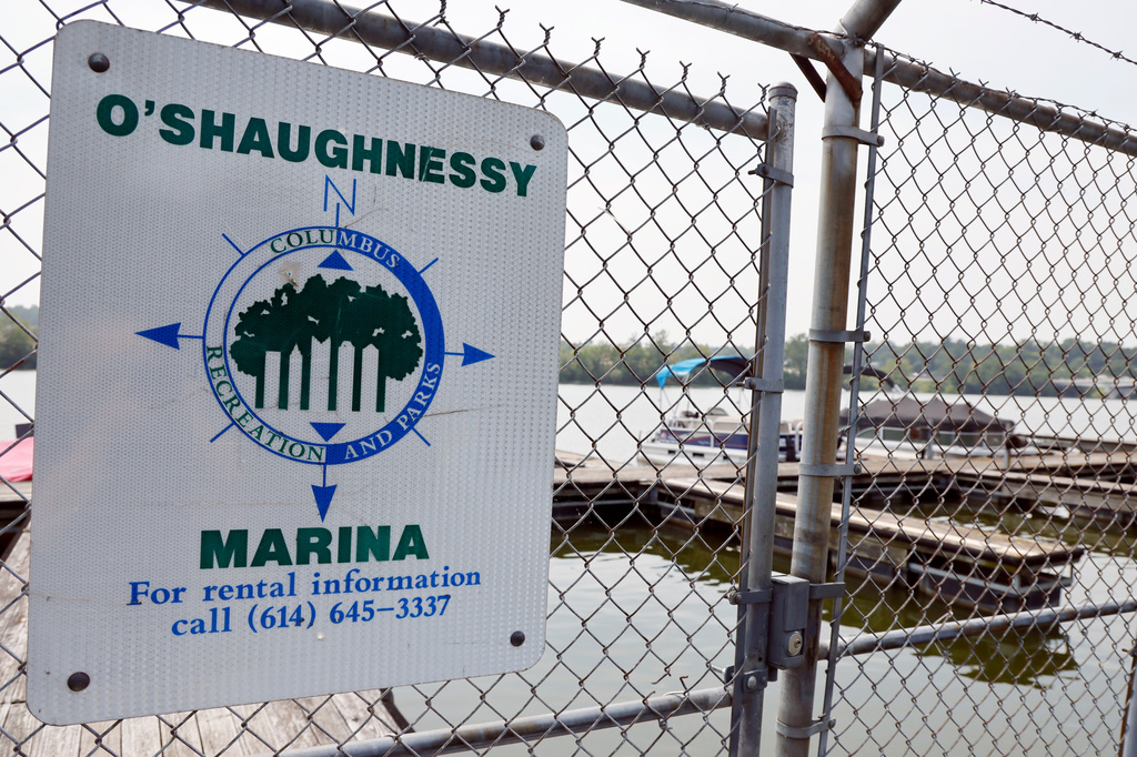 A sign is displayed on a fence along the Scioto River near where multiple people died after several of them went into the water to help another person who was struggling to swim Monday, July 20, 2026, in Powell, Ohio. (AP Photo/Jay LaPrete)